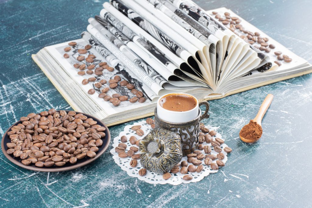 cup-of-foamy-coffee-plate-of-coffee-beans-and-book-on-marble-table-1